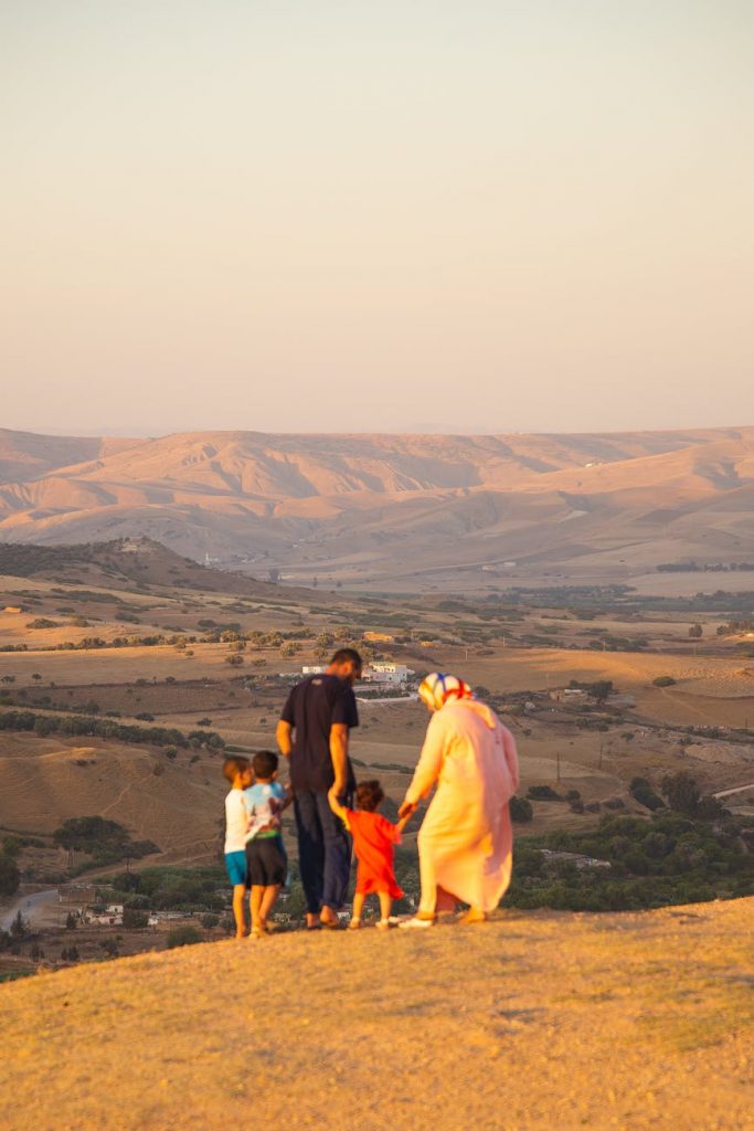 unrecognizable muslim family standing on hilltop and admiring highland view