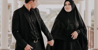 man in black suit holding hands with woman wearing black hijab